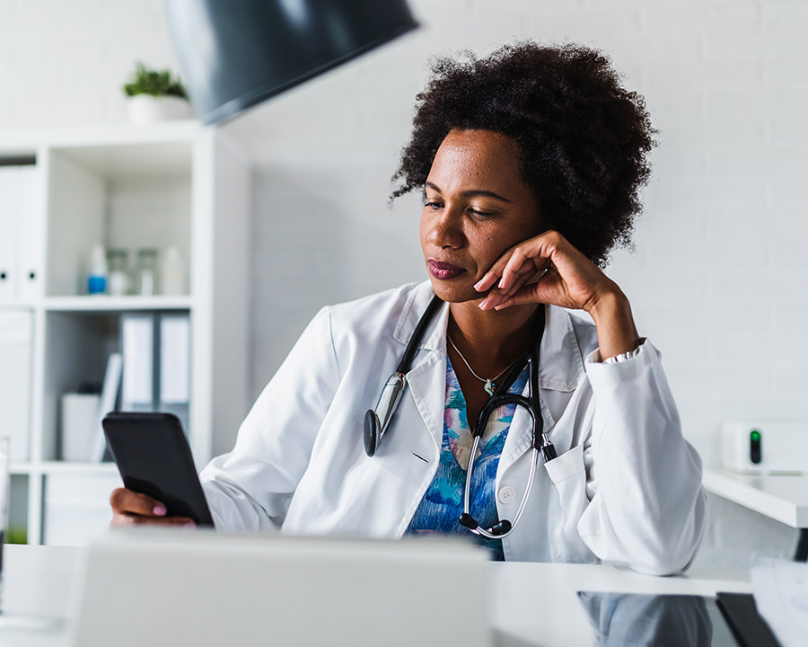 Doctor sitting at her desk and looking at her phone