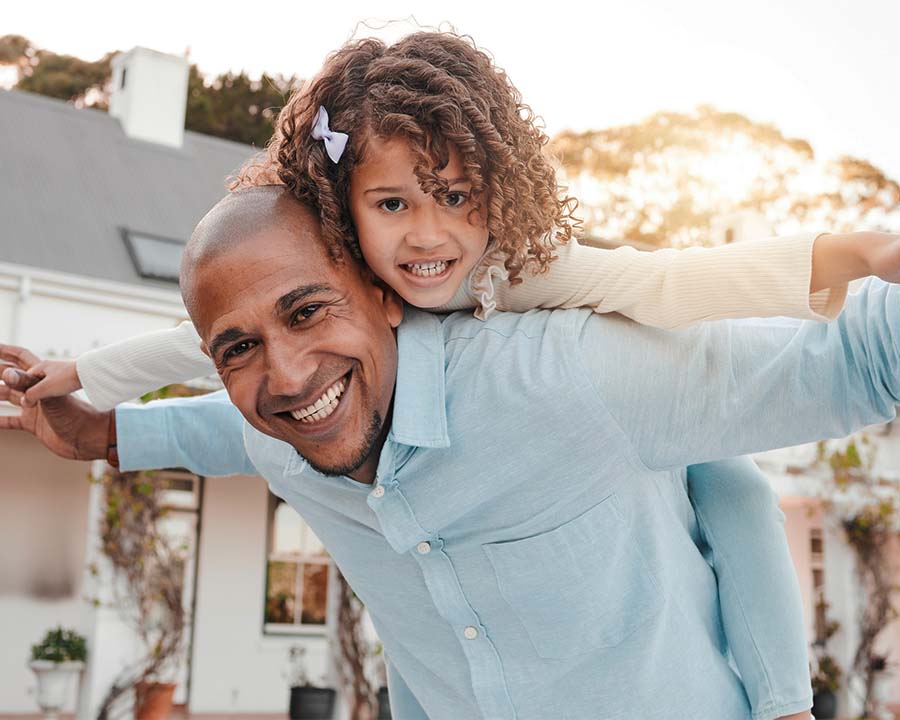 father giving daughter a piggy back ride outdoors