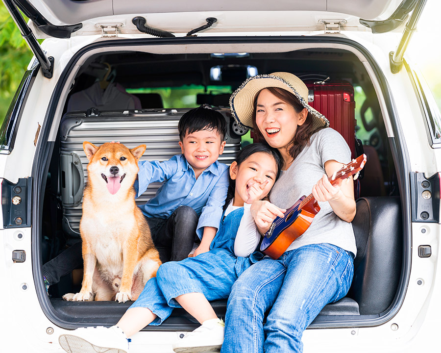 Happy family sitting in the trunk of their car