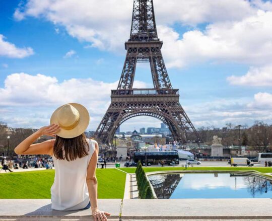 girl sitting on wall looking at Eifel tower