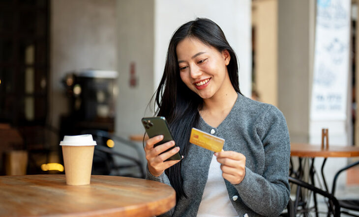 Woman with mobile phone using credit card