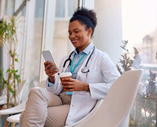 smiling doctor in white lab coat viewing cell phone