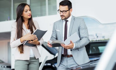 automobile salesman in dealership reviewing auto features with customer