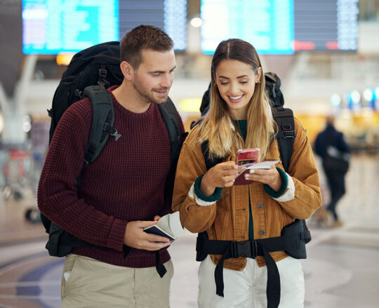 couple traveling at airport viewing mobile phone together