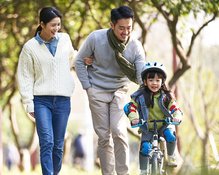 young couple teaching child how to ride a bike
