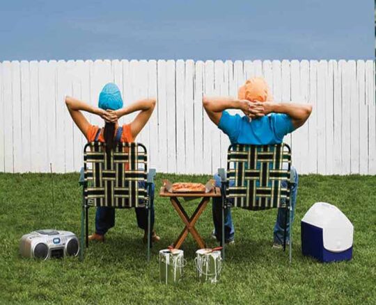 couple sitting in lawn chairs admiring newly painted fence