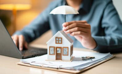 model of house positioned under small umbrella signifying a covered home