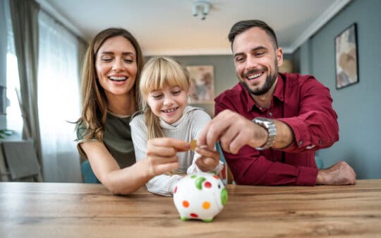 family placing coins in piggy bank