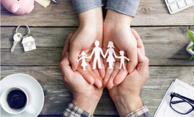 paper cut out of family resting within cupped hands