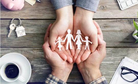 paper cut out of family resting within cupped hands