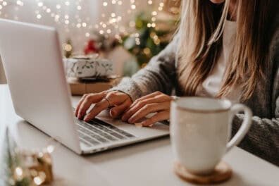 woman at laptop with holiday lights in background