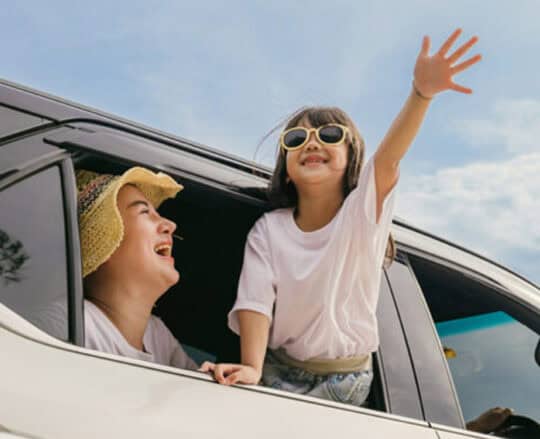 young girl in car waving hand outside of window
